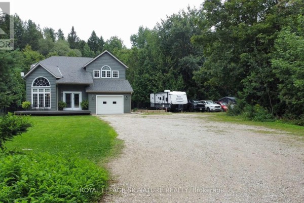 Long gravel driveway leading to a grey house with a trailer parked beside it. - 777320 Highway 10, Chatsworth