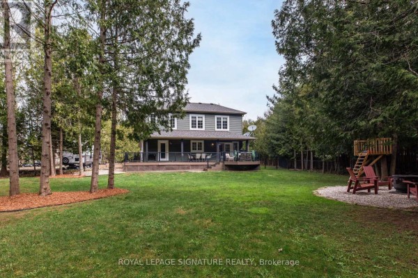 Side view of the house showing a fenced yard, gravel path, and covered deck. - 777320 Highway 10, Chatsworth
