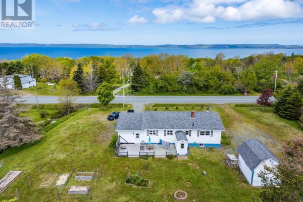 Wooden deck with a table and chairs, overlooking a grassy backyard with trees. - 7784 Highway 101, Plympton