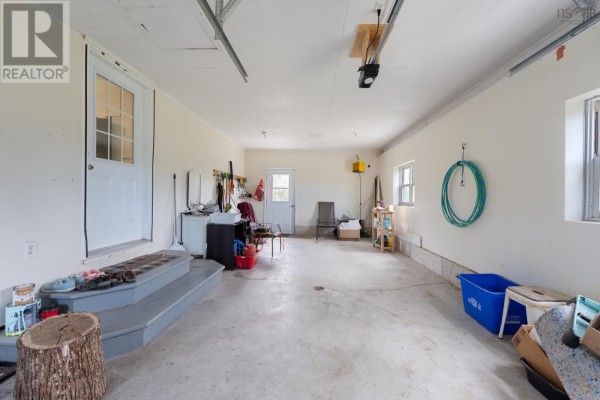 Backyard of the house with a deck, fire pit, and green lawn with surrounding trees. - 7784 Highway 101, Plympton