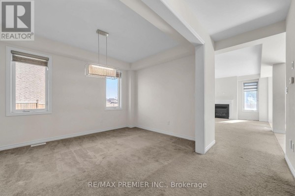 Empty room with grey carpet, beige walls, and a large window with natural light. - 7784 Tupelo Crescent, Niagara Falls