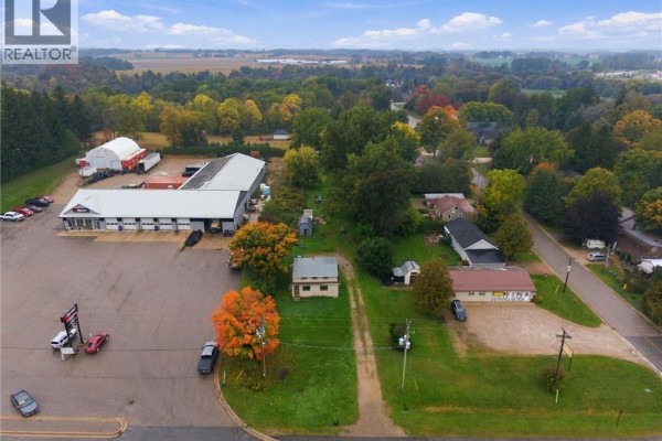 Aerial view of 77937 London Road, Clinton, showing the house, surrounding trees, and nearby commercial properties. - 77937 London Road, Clinton