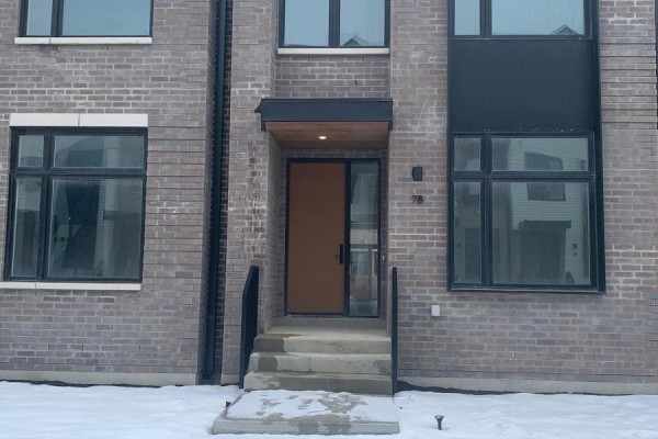Close-up of a townhouse entrance with grey brick, a brown door, and concrete steps. - 78 - 50 Lou Parsons Way S, Mississauga