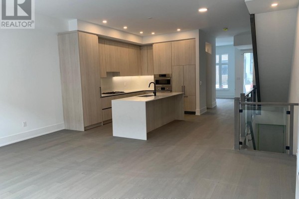 Open-concept living area and kitchen with a large island and light wood flooring. - 78 - 50 Lou Parsons Way S, Mississauga