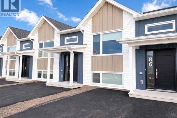 Close-up of townhouse exteriors featuring blue and tan siding, large windows, and dark doors. - 78-282 Jacques Street, Shediac