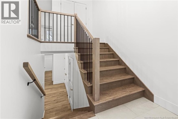 Interior staircase with light wood steps, white walls, and black metal railings. - 78-282 Jacques Street, Shediac