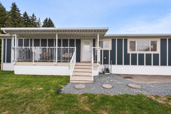 Front view of mobile home showcasing large windows and landscaped yard - 78 5742 Unsworth Road, Sardis South, Chilliwack