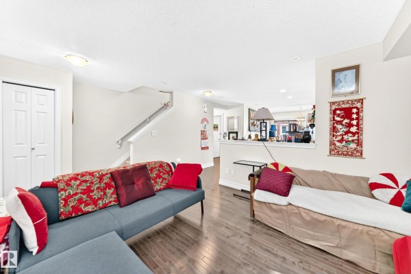 Living room with doorway to dining area, stairs, and white bi-fold closet doors. - #78 655 Tamarack Rd Nw, Edmonton