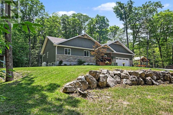 Side view of the house set on a grassy hill, surrounded by mature trees, with a stone retaining wall. - 78 Deerfield Drive, Mcnab/braeside
