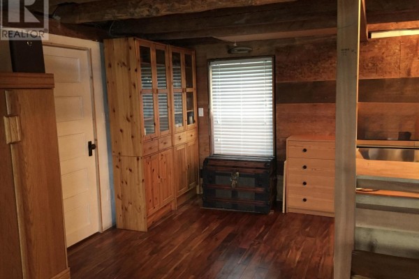 Room with wooden floors, wood-paneled walls, a large wooden cabinet, a trunk, and a chest of drawers. - 78 Marriotts Cove Road W, Marriotts Cove