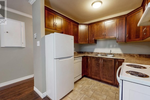 Kitchen with dark wood cabinets, white refrigerator, dishwasher, and white stovetop. - 78 Thorburn Road Unit#306, St John S
