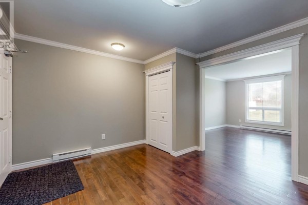 Entrance hallway with dark wood flooring, white doors, and a view into a living room. - 78 Thorburn Road Unit#306, St John S