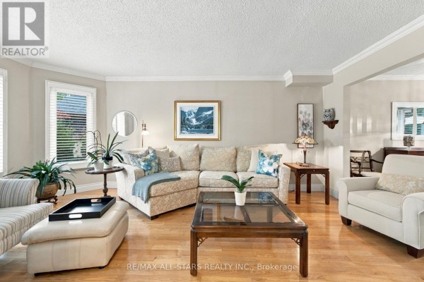 Living room with a sectional sofa, armchairs, coffee table, and large windows. - 78 Tilman Circle, Markham