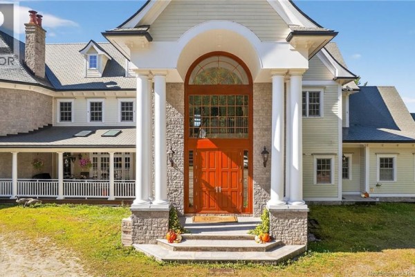 Close-up of the arched entryway with double red doors, stone facade, and white columns. - 78 Todd's Point Road, Dufferin