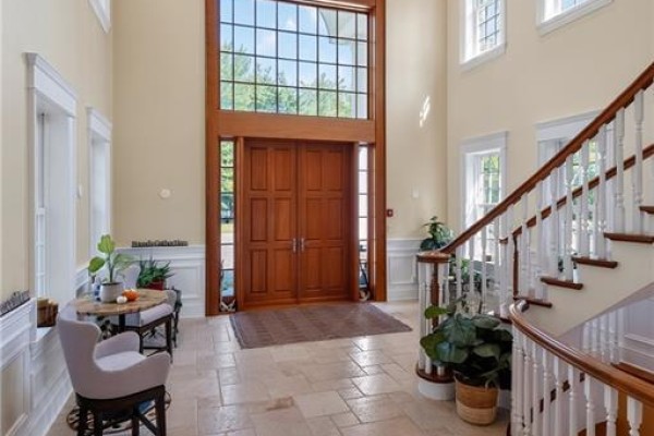 Interior foyer with cream walls, a wooden staircase, and a large double door with transom window. - 78 Todd's Point Road, Dufferin