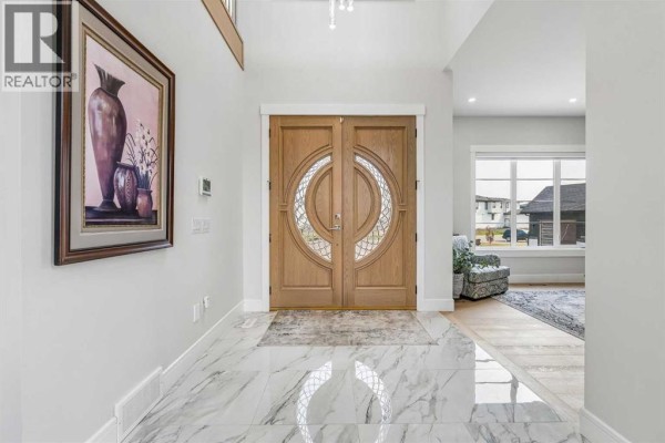Entrance foyer with marble tile flooring and double oak doors with glass inserts. - 78 Trinity Road, Rural Rocky View County