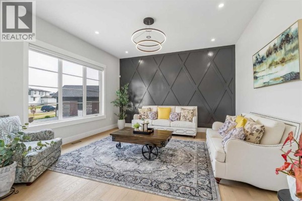 Living room with a large window, grey diamond-patterned accent wall, and two white sofas. - 78 Trinity Road, Rural Rocky View County