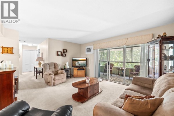 Living room with beige walls, neutral carpet, sofa, chairs, television, and balcony with seating. - 780 Houghton Road Unit# 408, Kelowna