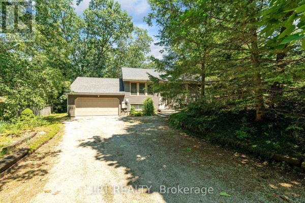 Side exterior of a house with grey siding, a brown garage door, and a concrete driveway. - 7806 Alfred Crescent, Lambton Shores