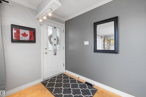 Interior entryway with grey walls, white door, black mirror, and Canadian flag art. - 7807 134 Av Nw, Edmonton