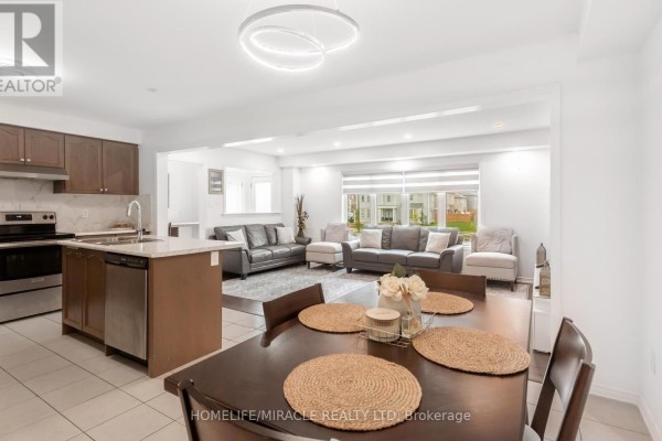 Open-concept kitchen and dining area adjacent to a living room with large windows. - 7808 Tupelo Crescent, Niagara Falls
