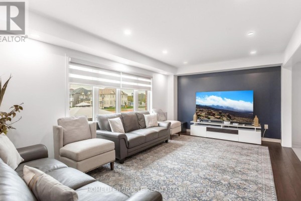 Living room featuring a dark blue accent wall, a television, and multiple seating arrangements. - 7808 Tupelo Crescent, Niagara Falls
