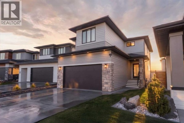 Aerial view of a suburban street showing rooftops, driveways, and backyards with fences. - 781 Atlantic Cove W, Lethbridge