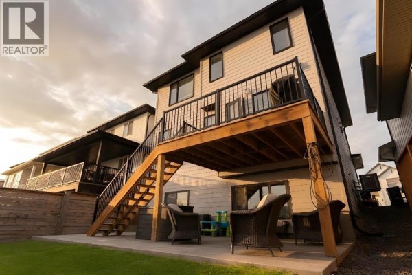 Open concept kitchen with white countertops, dark island, stainless steel appliances, and pendant lighting. - 781 Atlantic Cove W, Lethbridge