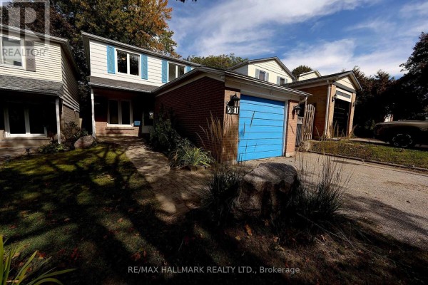 Front exterior of a two-story brick house with a blue garage door and a paved walkway. - 781 Pam Crescent, Newmarket