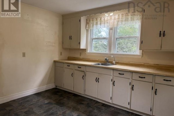 Kitchen with white cabinets, light wood countertops, and a sink below a window. - 7813 7 Highway, Musquodoboit Harbour