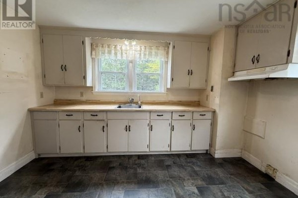 Kitchen showing white cabinets, light wood countertops, and a sink below a window. - 7813 7 Highway, Musquodoboit Harbour