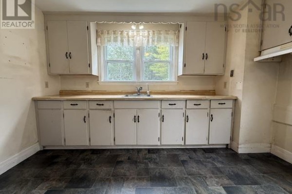 Kitchen showing white cabinets, light wood countertops, and a sink below a window. - 7813 7 Highway, Musquodoboit Harbour