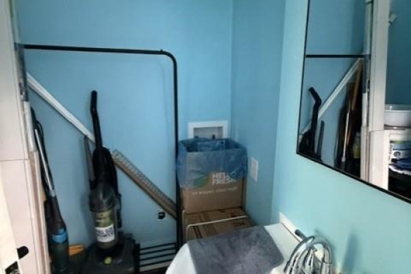 A corner of a room with a vacuum cleaner, storage boxes, and a laundry basket. - 7825 Route 3, Dewolfe