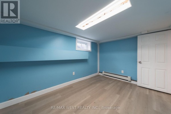 Finished basement with blue walls, wood-look flooring, and a fluorescent light fixture - 7826 Yonge Street Innisfil