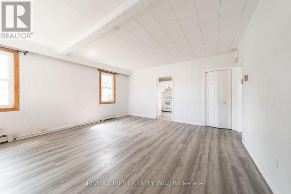 Living room with wood-paneled walls, laminate flooring, and a view into the kitchen - 7826 Yonge Street Innisfil