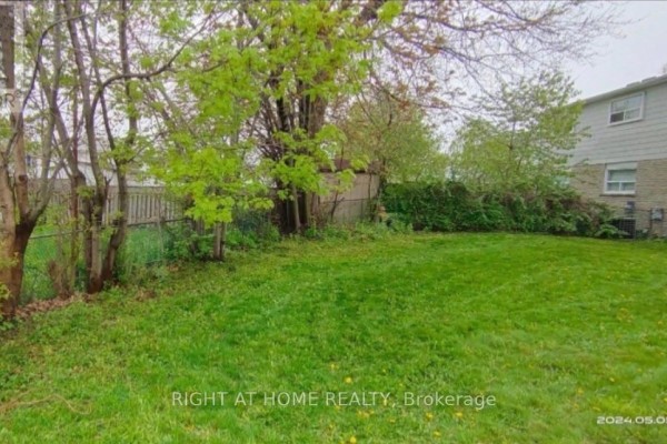 Backyard with green grass, trees, and a wooden fence. - 783 Consort Crescent, Mississauga