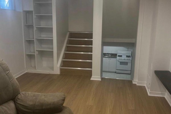 Basement living area with wood-look floor, white shelves, and a small kitchenette. - 783 Consort Crescent, Mississauga