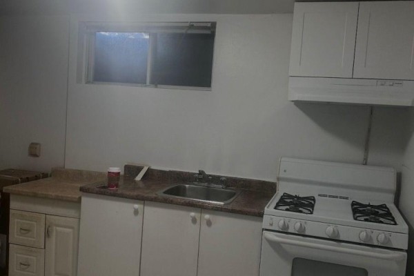 Small kitchen with white cabinets, oven, sink, and window. - 783 Consort Crescent, Mississauga