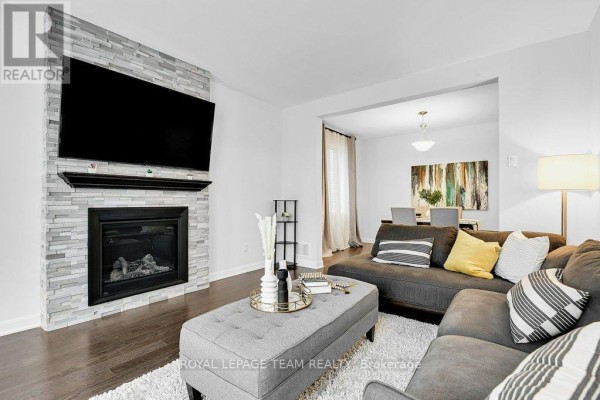 Living room with fireplace, TV, sectional sofa, and ottoman coffee table - 784 Cappamore Drive Ottawa