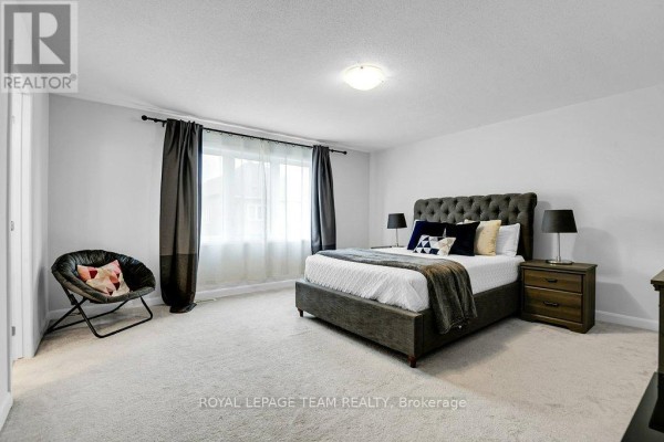 Bedroom with tufted headboard bed, accent chair, and large window - 784 Cappamore Drive Ottawa