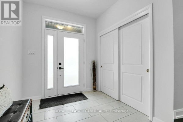 Curved staircase with dark wood treads and risers, metal balusters, and hardwood flooring in hallway. - 784 Cappamore Drive, Ottawa