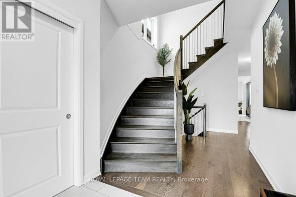 Home office with a wooden desk, ergonomic chair, computer, desk lamp, and artwork on white walls. - 784 Cappamore Drive, Ottawa