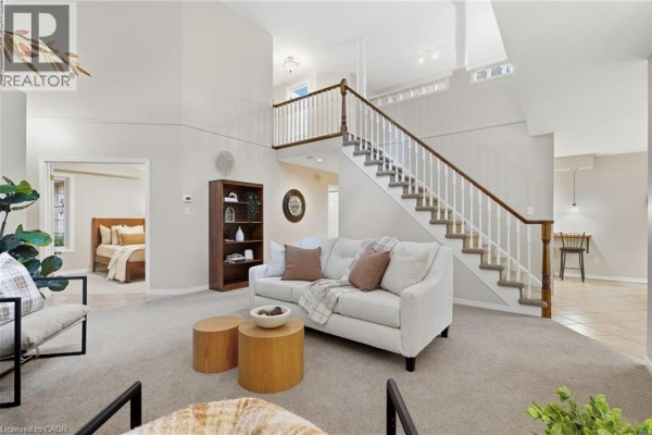 Living room with a sofa, staircase, bookcase, and view into a bedroom. - 784 Gordon Street Unit# 20, Guelph