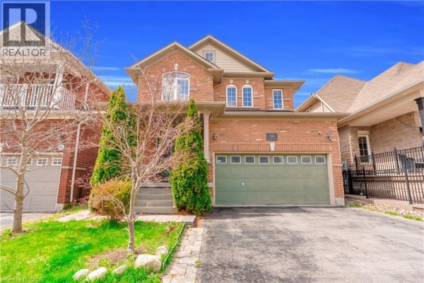Front exterior of a red brick two-story house with a green garage door. - 786 Fourth Line, Milton