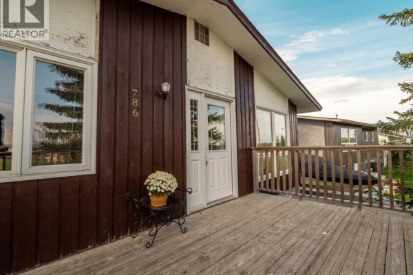 Entrance to the house with white door, large windows, and wooden siding. - 786 Isabel, Pincher Creek