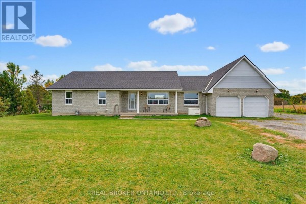 Front view of a light-colored brick bungalow with a green lawn and blue sky. - 7877 Canborough Road, Haldimand