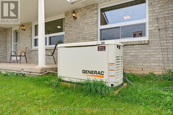 Close-up of a Generac generator on the grass next to a porch column. - 7877 Canborough Road, Haldimand