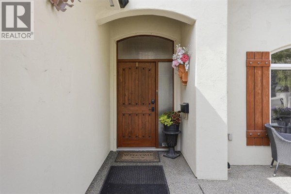 The wooden front door of the house, framed by a stucco archway and flanked by shutters. - 788 Rosewood Crescent, Kamloops