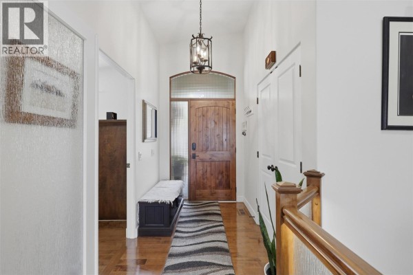 Interior hallway with a wooden front door, a bench, and a striped runner rug on hardwood floors. - 788 Rosewood Crescent, Kamloops