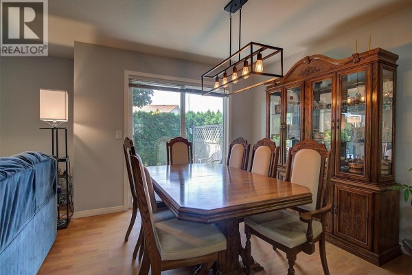 Formal dining room with a wooden table, upholstered chairs, and a glass-front cabinet. - 788 Rutland Road N Unit# 6, Kelowna